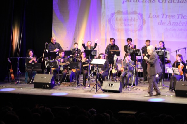 El ensamble celebra en el escenario con «¡Muchas Gracias!» proyectado al fondo, al cierre del concierto.